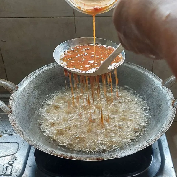 Panaskan minyak goreng sampai berasap dengan api sedang, lalu tuang adonan dengan posisi tinggi. Gunakan sendok berlobang agar adonan tersebar merata, goreng sampai matang. Balik setelah bagian bawah sudah matang.