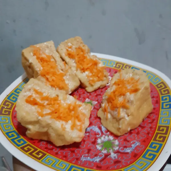 Masukan adonan ayam ke dalam tahu. Lalu beri wortel bagian atasnya.