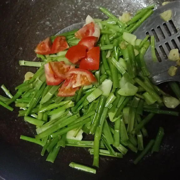 Masukkan potongan tomat dan batang kangkung kedalam wajan. Oseng campur aduk.