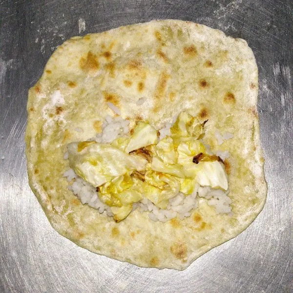 Ambil 1 lembar tortilla, kemudian tata nasi di atasnya, kol dan ayam geprek, kemudian gulung, sematkan lidi agar tidak terbuka.
