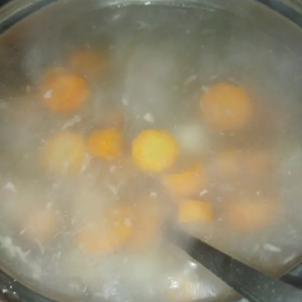 Masak air hingga mendidih, masukkan wortel dan bawang putih halus, masak hingga wortelnya setengah matang.