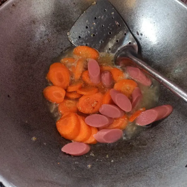 Setelah bumbu matang tambahkan air secukupnya lalu masukkan wortel dan sosis masak hingga wortel setengah matang.