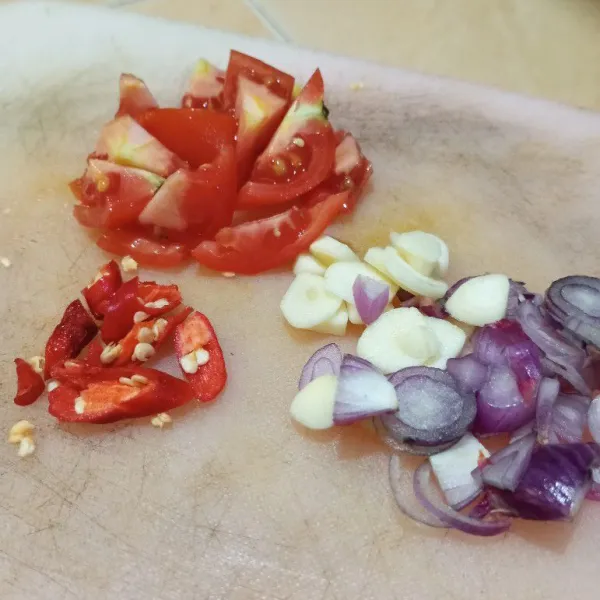 Siapkan talenan, iris cabe, tomat, bawang putih serta bawang merah.