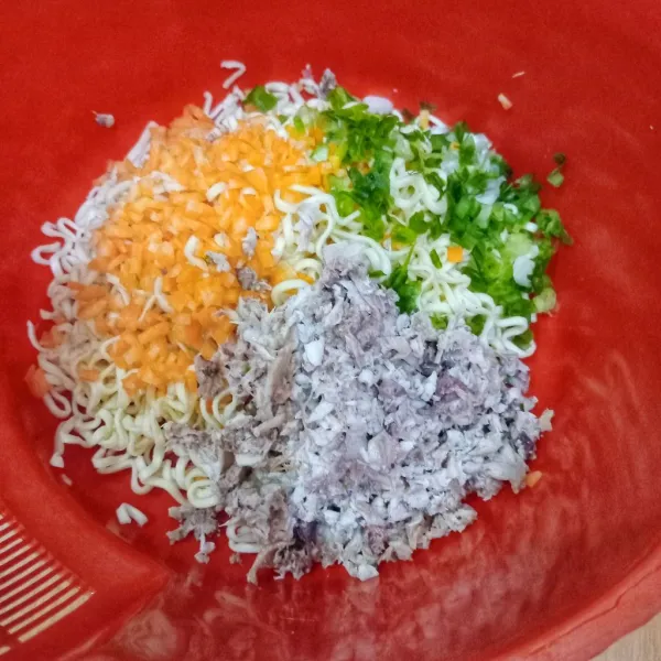 Campur mie, wortel cincang, daun bawang iris, telur, daging ayam cincang, bawang putih cincang, garam, kaldu jamur dan merica bubuk, aduk rata.