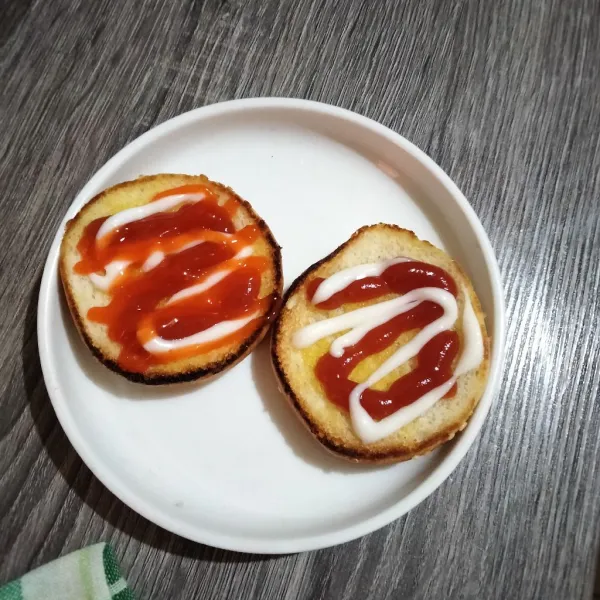 Olesi burger bun dengan saos tomat dan mayonaise. Untuk versi pedas ditambah saos sambal