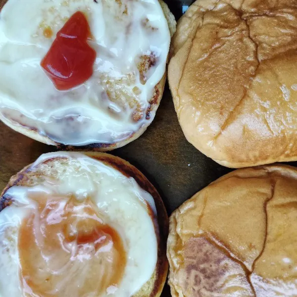 Olesi burger bun dengan mayonnaise dan saus tomat.