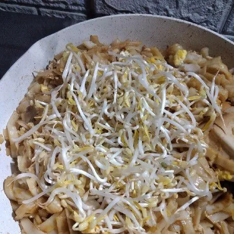 Masukkan tauge, aduk cepat, lalu masukkan tumisan ayam, masak kwetiau hingga semua bahan tercampur rata.
