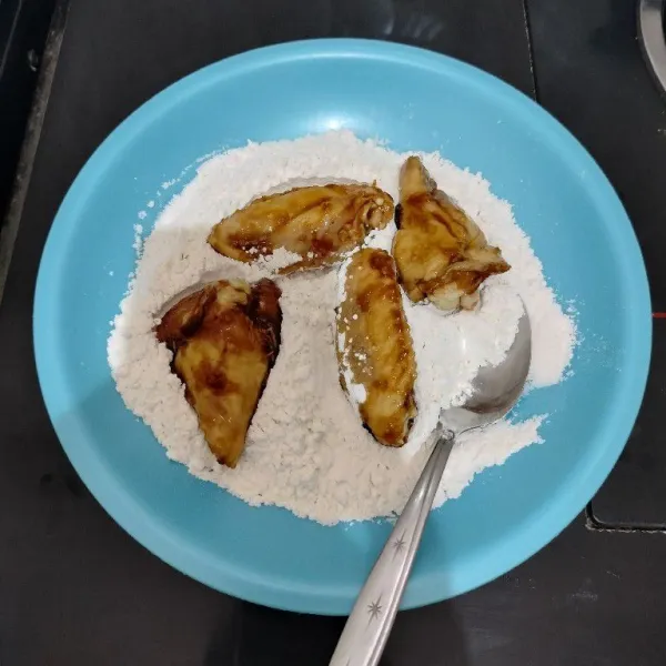Lalu gulingkan sayap ayam ke dalam campuran tepung. Cubit perlahan agar tepung menempel.
