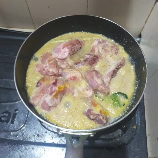 Cuci bersih ayam. Blender halus bawang putih dan lengkuas. Masukkan ke dalam wajan lalu masukkan ketumbar, bubuk kunyit, daun jeruk, sereh, dan garam. Ungkep ayam dengan api sedang sampai air menyusut sambil sesekali di aduk.