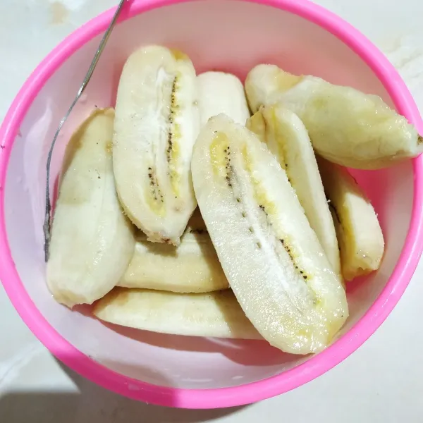 Belah buah pisang menjadi dua bagian, sisihkan.