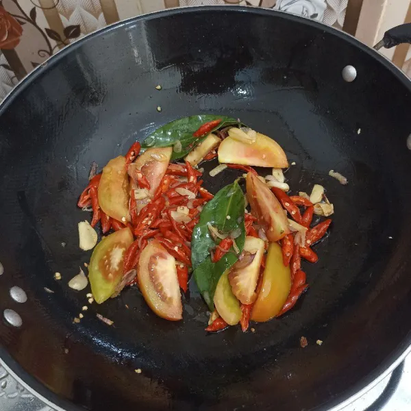 Tumis bawang merah dan bawang putih hingga harum lalu masukkan tomat, cabe, daun salam, lengkuas. Aduk merata.