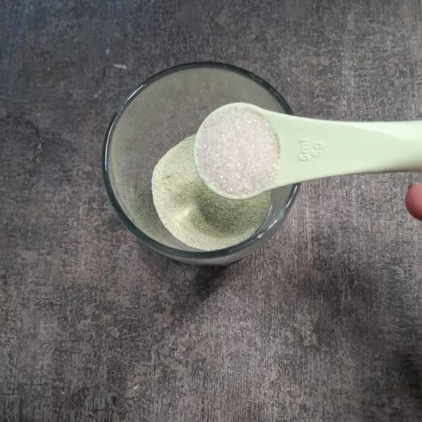 Tuang bubuk minuman matcha, susu bubuk ke dalam gelas, lalu tambahkan gula pasir.