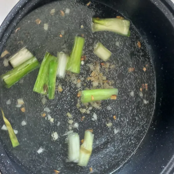 Masukkan daun bawang aduk hingga layu lalu tuang air, masak hingga mendidih.