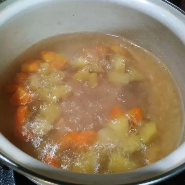 Masak air sampai mendidih. Masukkan wortel dan kentang masak hingga setengah matang.