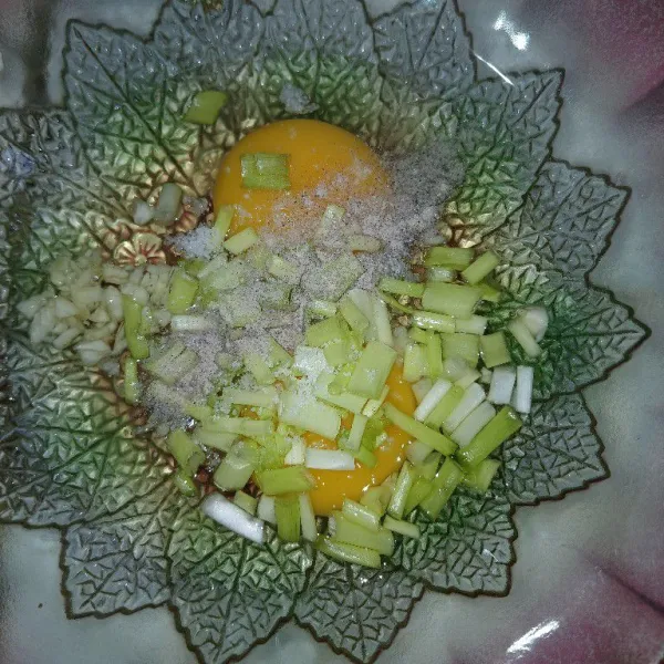 Dalam wadah mangkuk, campur telur dengan bawang putih cincang, irisan daun bawang, garam dan lada bubuk. Kocok lepas.