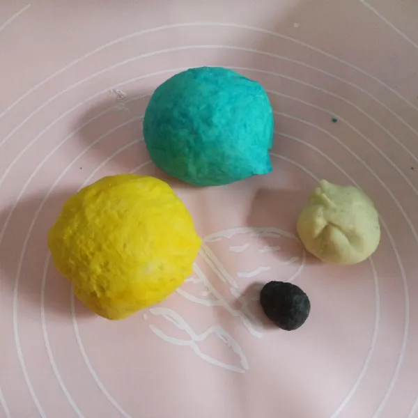 Ambil 3 gr adonan untuk adonan hitam, ambil adonan putih sebanyak 25 gr sisanya bagi sama banyak untuk diberi warna biru dan kuning. Istirahatkan sebentar selama 10 menit.