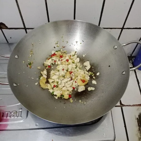 Hancurkan tahu dengan spatula sambil diaduk rata.