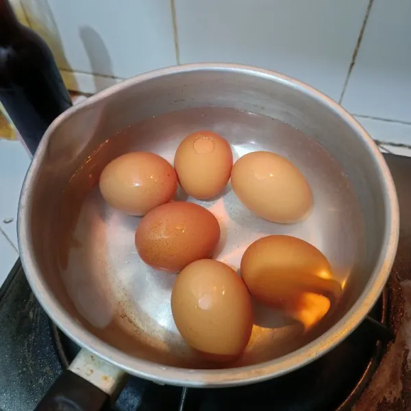 Rebus telur hingga matang. Setelah matang, buang airnya dan ganti dengan air dingin lalu kupas telurnya.