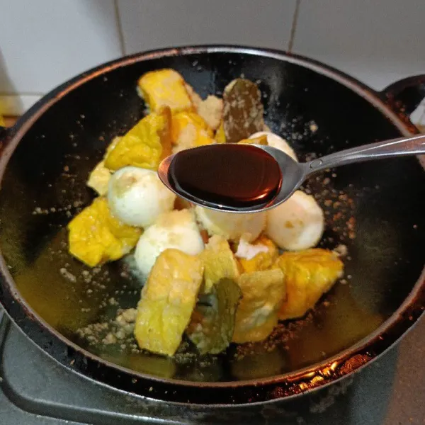 Masukkan telur rebus dan tahu kuning, beri kecap manis, aduk rata kemudian tambahkan air.