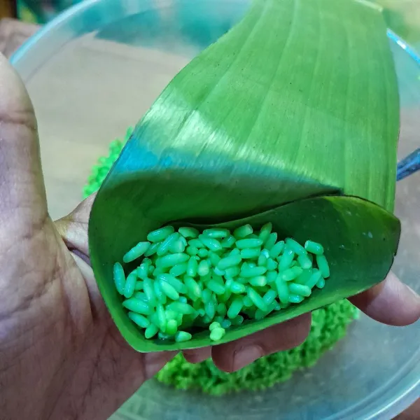 Ambil selembar daun pisang lalu beri isian 30 gr beras ketan sambil dipadatkan dan bentuk menyerupai segitiga. Sematkan tusuk lidi untuk mengunci isian.