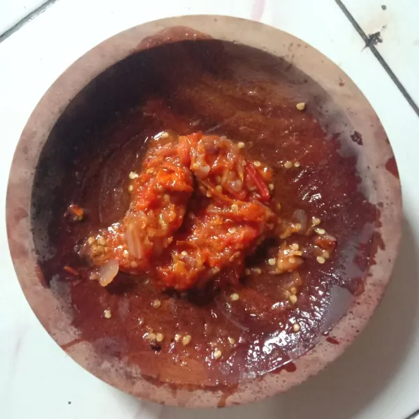 Ulek sambal sampai dirasa halus, lalu tambahkan minyak goreng panas bekas menggoreng tadi, aduk-aduk.