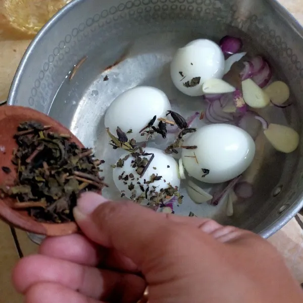 Masukkan telur yang sudah dikupas pada panci berisi air, tambahkan irisan bawang merah dan bawang putih serta teh