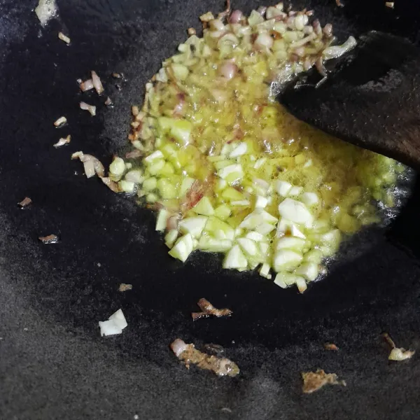 Masukkan cincangan bawang putih dan tumis hingga bawang putih kuning dan layu.