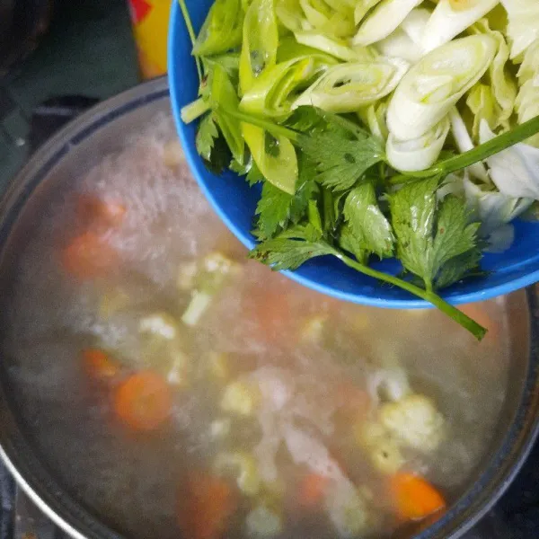 Setelah mendidih, tambahkan wortel, kentang dan daun bawang masak sampai sayur empuk.