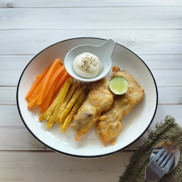 Tata ikan, kentang, wortel dan mayonaise yang sudah ditaburi parsley dan air perasan jeruk lemon di atas piring. Siap disajikan.