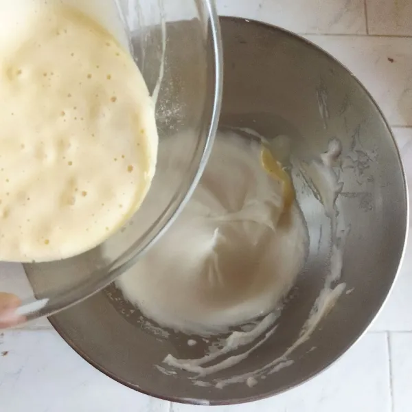 Masukkan meringue ke dalam adonan tepung secara berkala, aduk perlahan menggunakan spatula hingga tercampur rata.