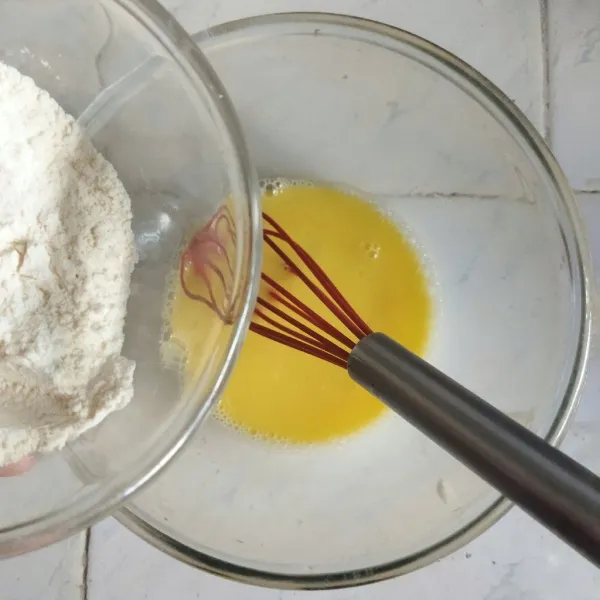 Masukkan kuning telur, susu, air jeruk lemon, vanilla extract, dan garam ke dalam adonan tepung. Aduk rata dengan whisker hingga membentuk adonan.