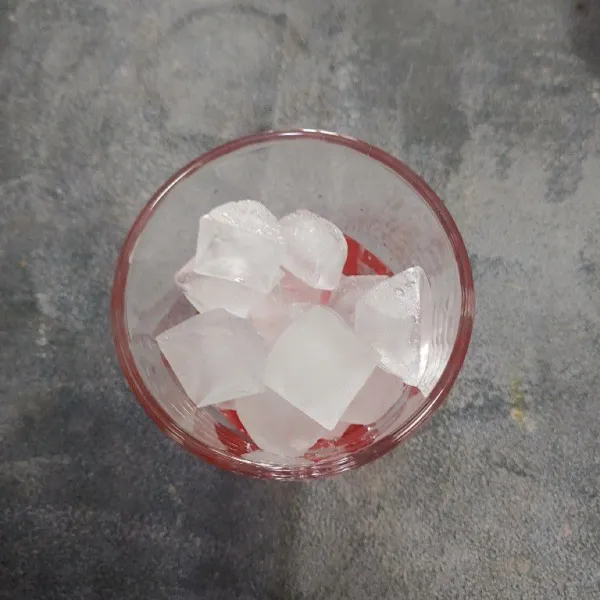 Siapkan gelas saji, tuang sirup cocopandan di dasar gelas tambahkan es batu.