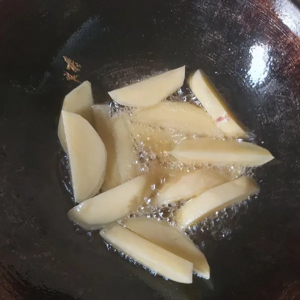 Kupas dan potong memanjang kentang lalu goreng hingga setengah matang.