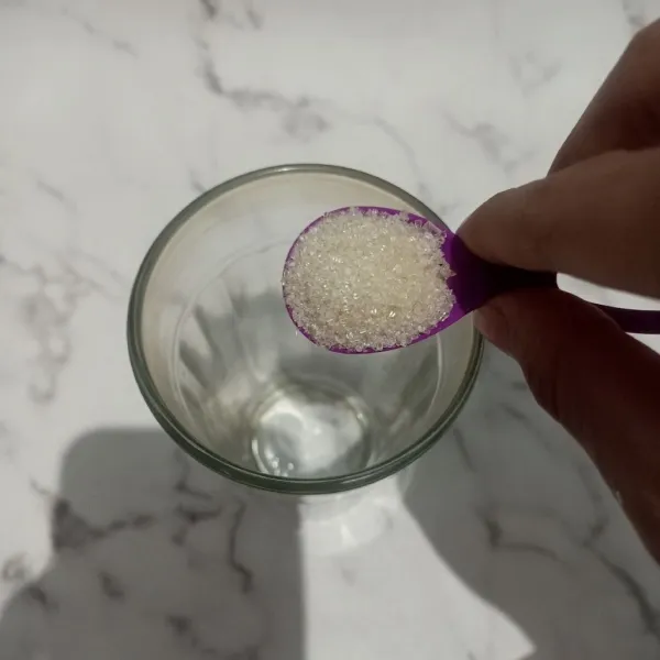 Siapkan gelas saji lalu tambahkan gula pasir ke dalam gelas saji