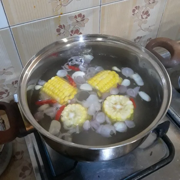 Didihkan air, lalu masukkan bawang merah, bawang putih, cabe keriting merah dan jagung. Masak hingga jagung matang.