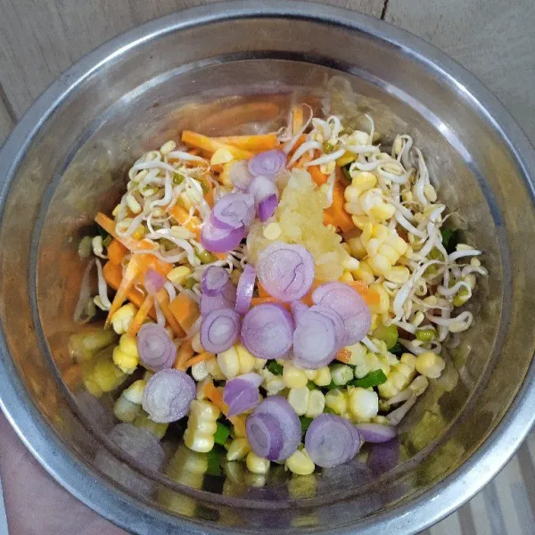 Dalam wadah, campur sayuran dengan bawang putih dan bawang merah.