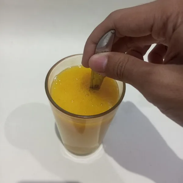 Tambahkan es batu dan aduk jus mangga dan susu kental manis hingga larut