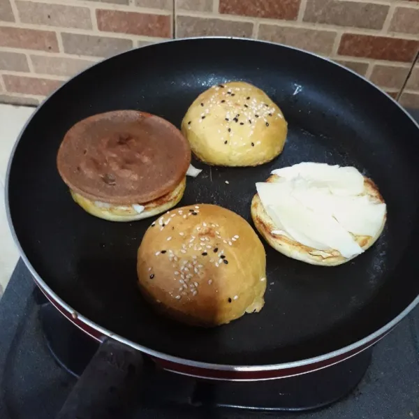 Beri mozarella di atas burger bun, dan tumpuk dengan daging burger panas agar mozarella meleleh.
