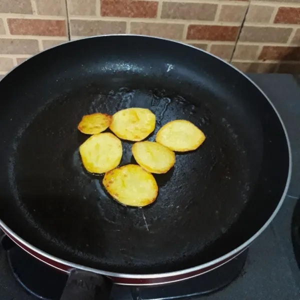 Kupas kentang dan iris tipis. Kemudian goreng kentang dengan margarin hingga matang, sisihkan.