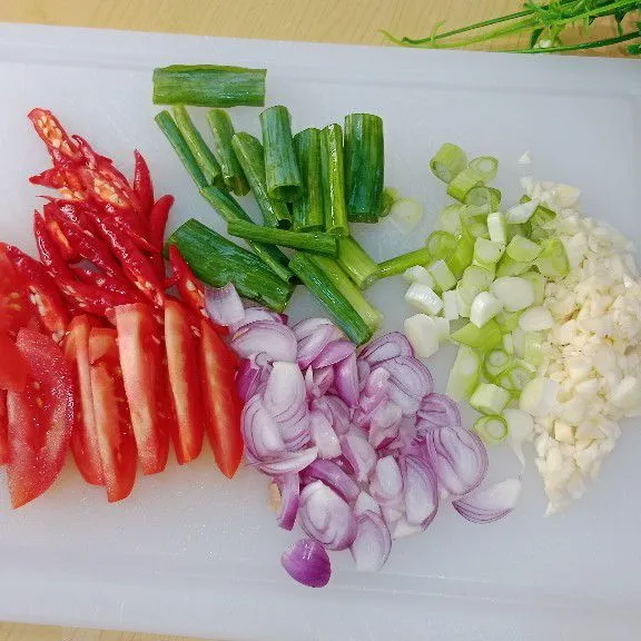 Cincang halus bawang putih lalu diiris tipis bawang merah, daun bawang, tomat merah dan cabai merah.