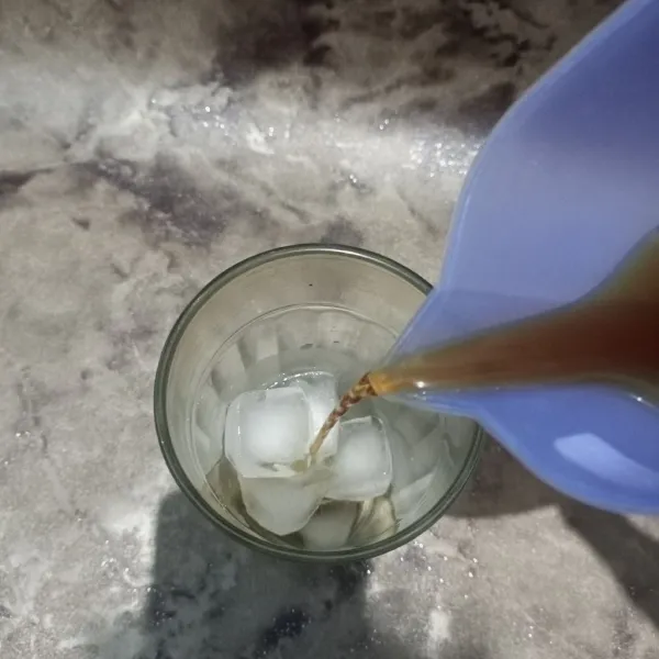 Tuangkan soda ke dalam gelas saji berisi es batu