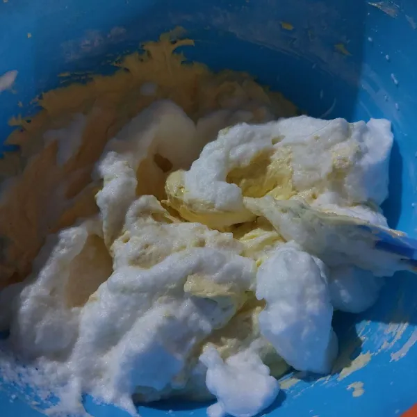 Kocok putih telur hingga soft peak, lalu tambahkan ke adonan kuning telur bertahan, aduk hingga tercampur rata
