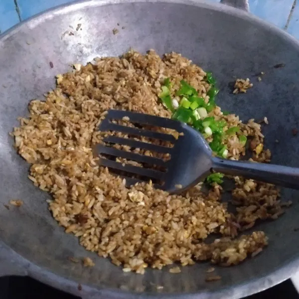 Setelah rata berikan daun bawang, masak sambil pisahkan nasi yang bergumpal.
