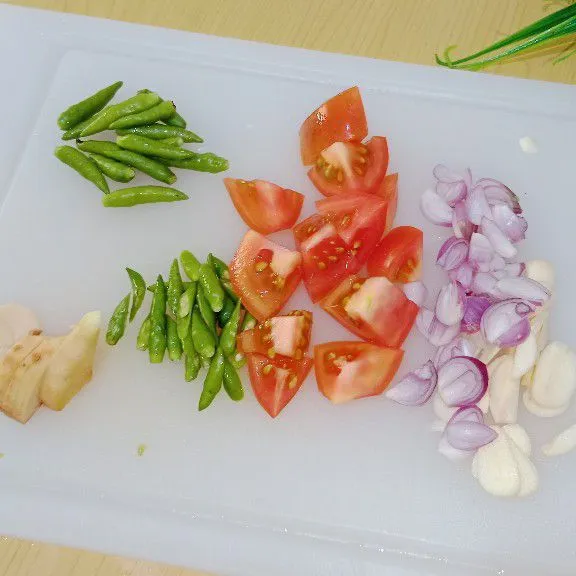 Diiris tipis bawang putih, bawang merah, tomat merah, cabai rawit dan lengkuas