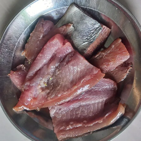 Cuci bersih ikan tuna, lumuri dengan perasan jeruk purut. Diamkan selama 10 menit