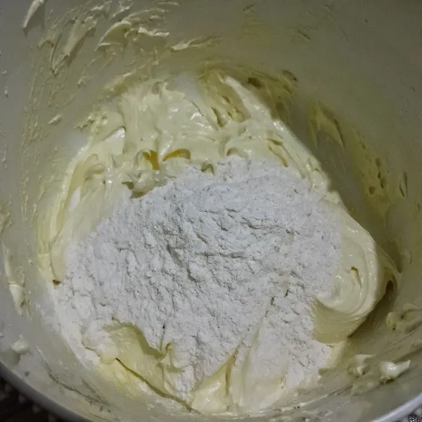 Campur jadi satu tepung terigu, tepung custard, susu bubuk, ayak. Masukkan ayakan tepung  kedalam adonan butter, margarin dan telur yang di mixer tadi. Aduk dengan spatula kue hingga tercampur dengan baik.
