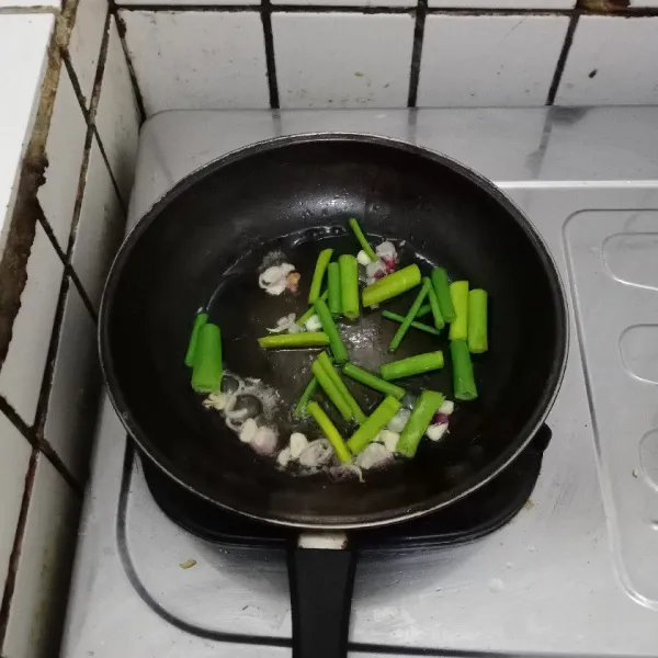 Tumis bawang merah dan bawang putih. Masukkan bunga bawang, masak hingga layu.