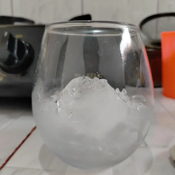 Masukan es batu kedalam gelas saji.