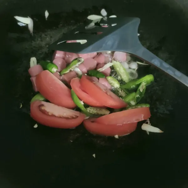 Tumis irisan bawang merah putih hingga harum, masukan sosis tumis sebentar, masukan potongan tomat dan cabe tumis setengah layu