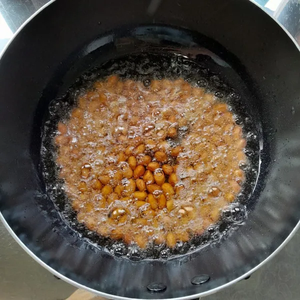 Panaskan secukupnya minyak dalam wajan, masukkan kacang. Goreng hingga kacang matang. Angkat, tiriskan dan biarkan hingga suhu ruang. Kemudian blender kacang hingga halus. Sisihkan.